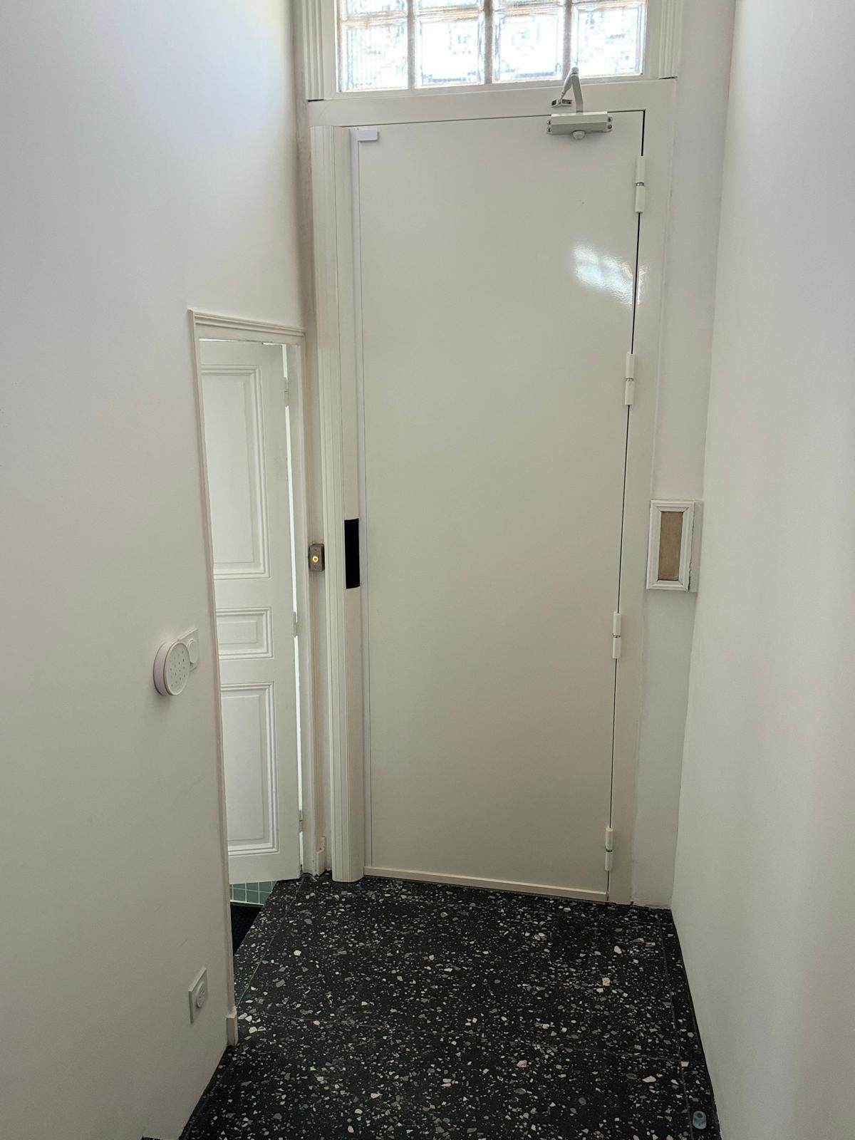 Porte blindée blanche avec ferme-porte en immeuble